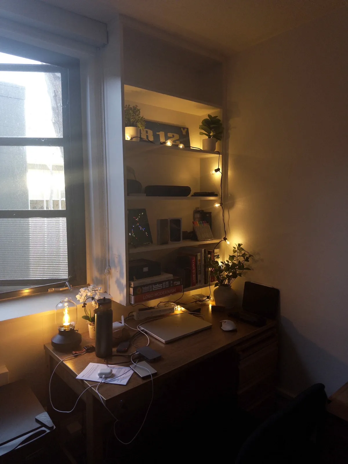 A desk and shelves lit by string lights.