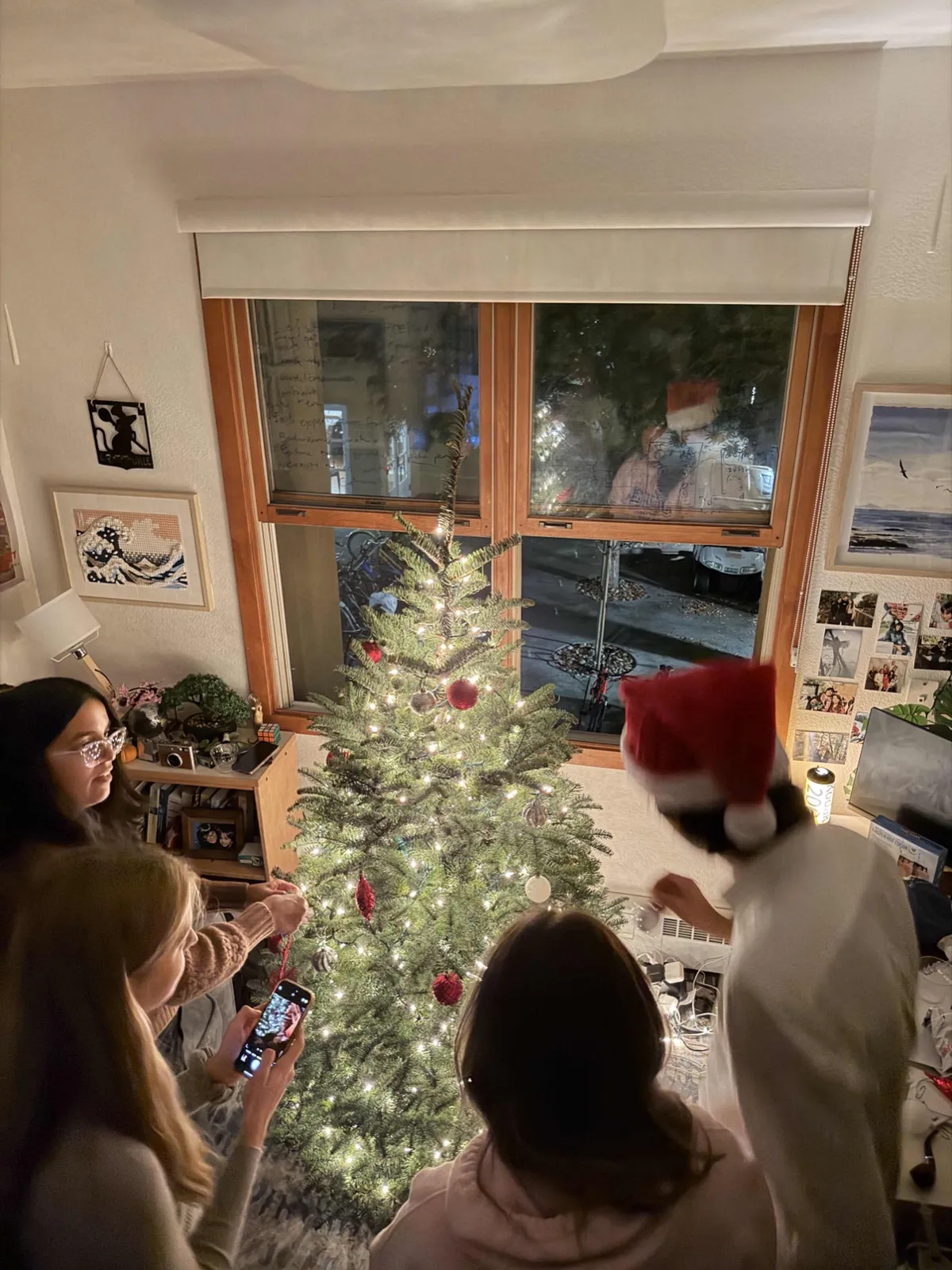 Students decorating a Christmas tree in a dorm room.
